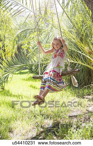 Girl sitting swinging on tree swing in garden View Large Photo Image Stock Image - Girl sitting swinging on tree swing in garden. Fotosearch