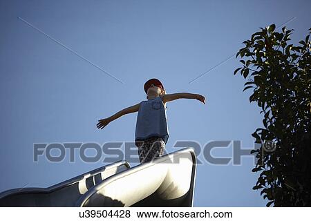 Girl standing with arms open at top of park slide View Large Photo Image Stock Photo - Girl standing with arms open at top of park slide. Fotosearch