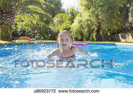 Stock Image - Girl swimming in garden swimming pool. Fotosearch