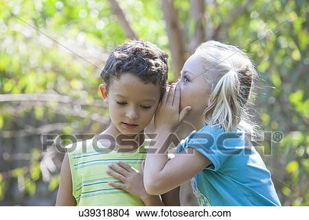 Girl whispering to boy in garden View Large Photo Image Picture - Girl whispering to boy in garden. Fotosearch