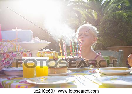 Stock Photo - Girls blowing out candles on birthday cake. Fotosearch