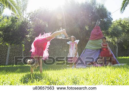 Girls watching friend in fairy costume doing handstand in garden View Large Photo Image Stock Image - Girls watching friend in fairy costume doing handstand in garden. Fotosearch