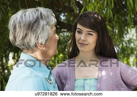 Stock Photograph - Grandmother and granddaughter having conversation in garden. Fotosearch