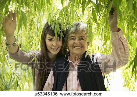 Stock Photograph - Grandmother and granddaughter under willow tree. Fotosearch