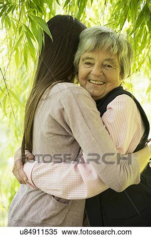Stock Photography - Grandmother and granddaughter under willow tree. Fotosearch