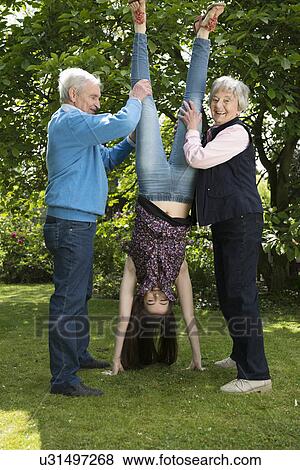 Stock Photo - Grandparents and granddaughter doing acrobatics in garden. Fotosearch