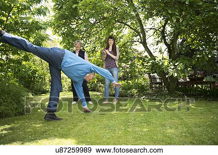 Grandparents and granddaughter doing acrobatics in garden View Large Photo Image Stock Photo - Grandparents and granddaughter doing acrobatics in garden. Fotosearch