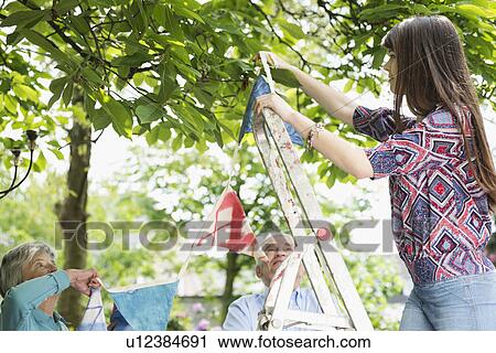 Grandparents and granddaughter hanging up bunting View Large Photo Image Stock Image - Grandparents and granddaughter hanging up bunting. Fotosearch