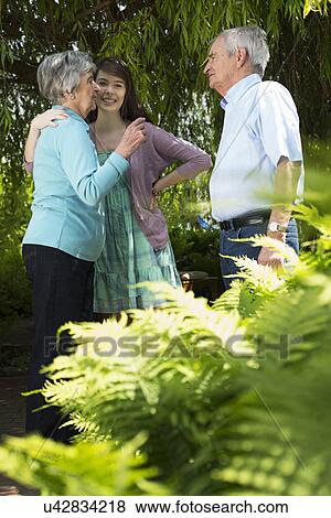 Grandparents and granddaughter having conversation in garden View Large Photo Image Stock Photo - Grandparents and granddaughter having conversation in garden. Fotosearch