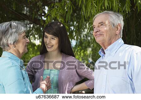 Grandparents and granddaughter having conversation in garden View Large Photo Image Stock Photo - Grandparents and granddaughter having conversation in garden. Fotosearch