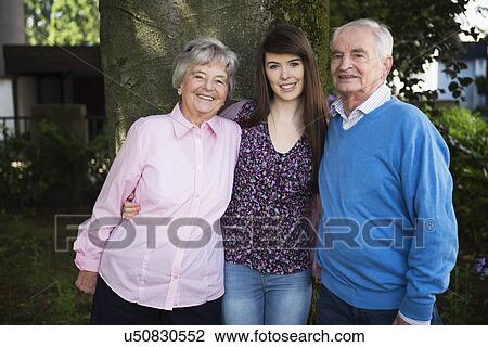Grandparents and granddaughter standing by tree View Large Photo Image Stock Image - Grandparents and granddaughter standing by tree. Fotosearch