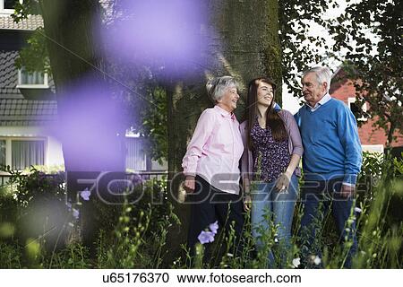 Grandparents and granddaughter standing by tree View Large Photo Image Stock Image - Grandparents and granddaughter standing by tree. Fotosearch