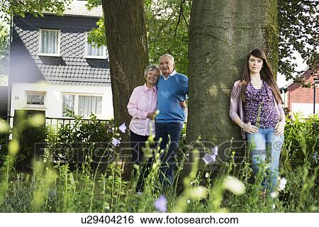 Grandparents and granddaughter standing by tree View Large Photo Image Stock Photograph - Grandparents and granddaughter standing by tree. Fotosearch
