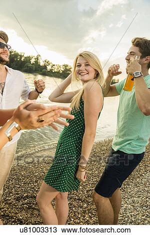 Stock Image - Group of friends dancing on beach. Fotosearch
