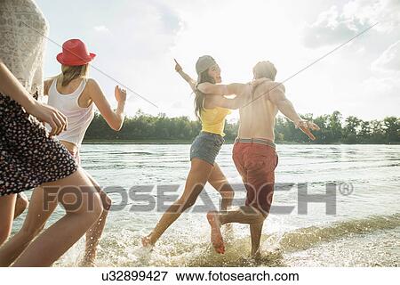 Stock Photo - Group of friends running in lake. Fotosearch