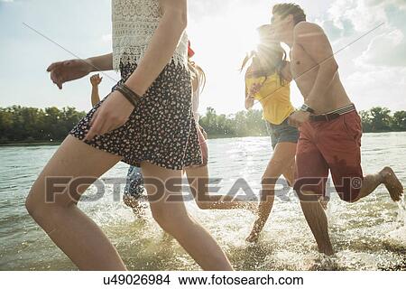 Picture - Group of young friends running in lake. Fotosearch