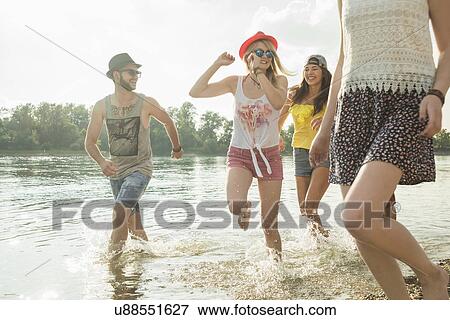 Stock Photo - Group of young friends running in lake. Fotosearch