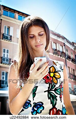 Impatient young woman looking at smartphone on city street View Large Photo Image Picture - Impatient young woman looking at smartphone on city street. Fotosearch