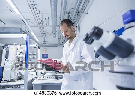 Stock Photograph - Lab assistant checking details on clipboard. Fotosearch