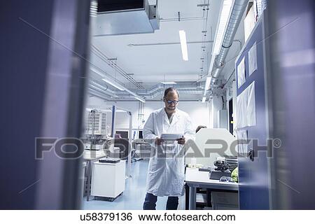 Stock Photograph - Lab assistant checking details on digital tablet. Fotosearch