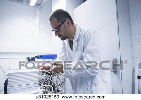 Stock Photo - Lab assistant working on equipment. Fotosearch