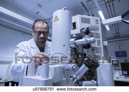 Stock Image - Lab assistant working on microscope. Fotosearch