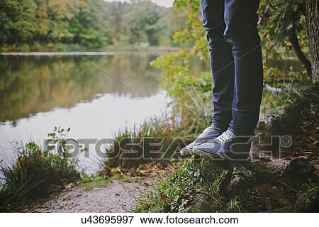 Legs of young man standing on fallen tree on riverbank View Large Photo Image Stock Photo - Legs of young man standing on fallen tree on riverbank. Fotosearch