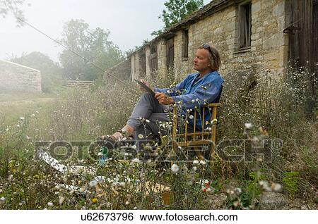 Man sitting sketching outside farm buildings View Large Photo Image Stock Photograph - Man sitting sketching outside farm buildings. Fotosearch