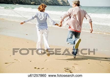 Mature couple holding hands running on beach, Camaret-sur-mer, Brittany, France View Large Photo Image Stock Image - Mature couple holding hands running on beach, Camaret-sur-mer, Brittany, France. Fotosearch