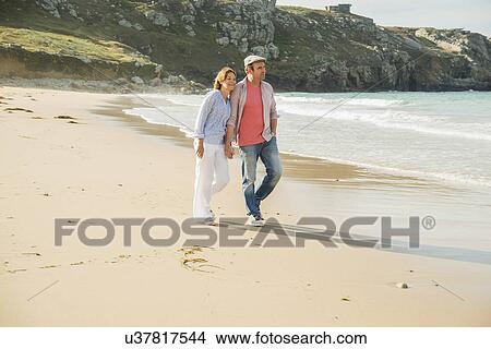 Mature couple holding hands strolling on beach, Camaret-sur-mer, Brittany, France View Large Photo Image Picture - Mature couple holding hands strolling on beach, Camaret-sur-mer, Brittany, France. Fotosearch