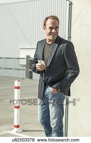 Stock Photo - Mature man holding smartphone. Fotosearch
