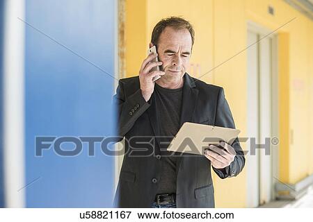 Mature man on smartphone using digital tablet View Large Photo Image Stock Photo - Mature man on smartphone using digital tablet. Fotosearch