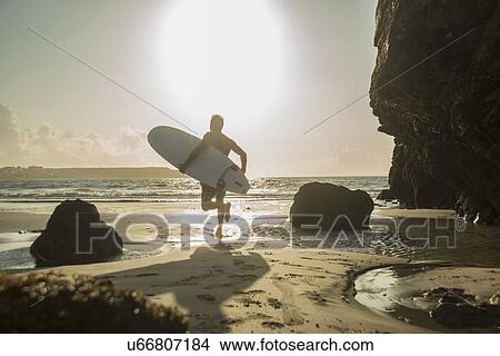 Picture - Mature man running towards sea, holding surf board. Fotosearch