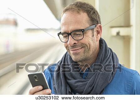 Stock Image - Mature man using smartphone. Fotosearch