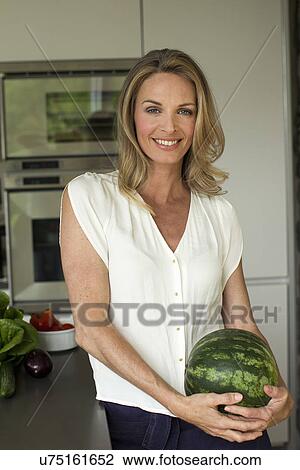 Stock Image - Mature woman holding watermelon. Fotosearch