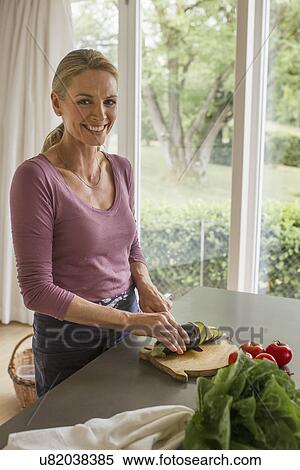 Stock Photography - Mature woman slicing aubergine. Fotosearch