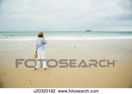 Mature woman strolling on beach chatting on smartphone, Camaret-sur-mer, Brittany, France View Large Photo Image Stock Image - Mature woman strolling on beach chatting on smartphone, Camaret-sur-mer, Brittany, France. Fotosearch