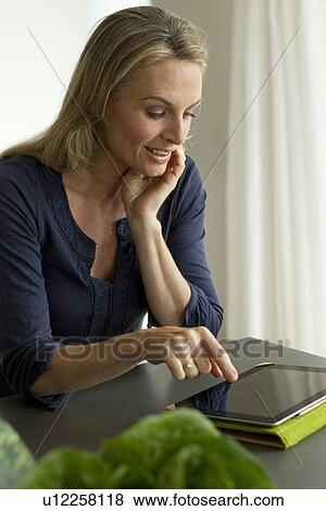 Stock Photo - Mature woman using digital tablet. Fotosearch
