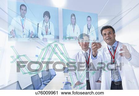 Stock Image - Medical specialists discussing results through video conference on futuristic display. Fotosearch