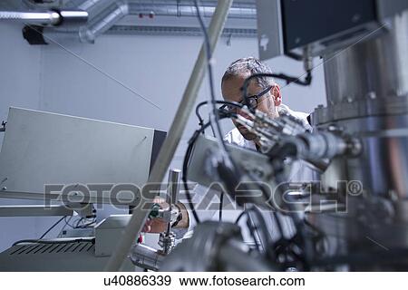 Stock Photo - Microscopy lab assistant working on equipment. Fotosearch