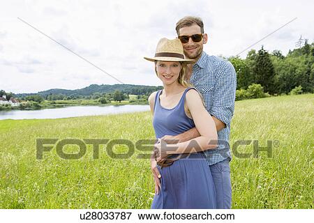 Stock Photo - Mid adult couple in field, portrait. Fotosearch