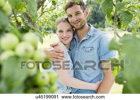 Stock Image - Mid adult couple with arms around each other. Fotosearch