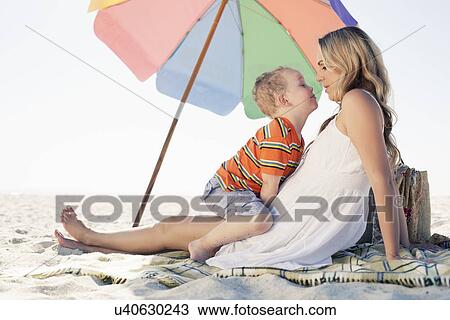 Stock Image - Mid adult mother and son picnic blanket at beach, Cape Town, Western Cape, South Africa. Fotosearch