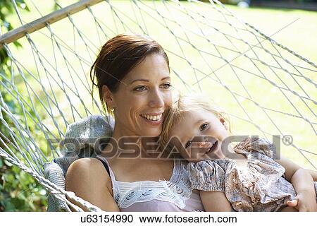 Mid adult mother and toddler daughter reclining in garden hammock View Large Photo Image Stock Image - Mid adult mother and toddler daughter reclining in garden hammock. Fotosearch
