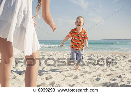 Stock Image - Mid adult mother playing with young son on beach, Cape Town, Western Cape, South Africa. Fotosearch