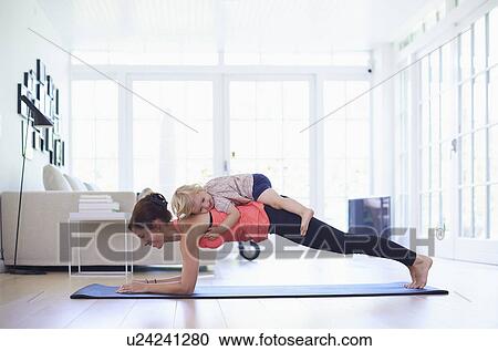 Mid adult mother practicing yoga with toddler daughter on top of her View Large Photo Image Stock Image - Mid adult mother practicing yoga with toddler daughter on top of her. Fotosearch