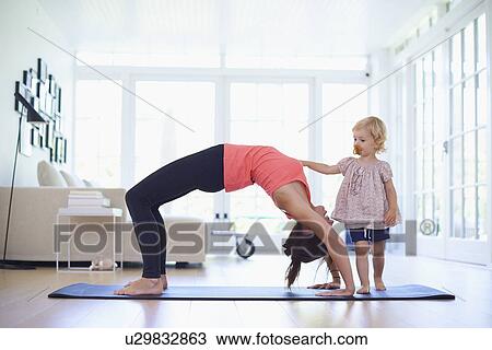 Mid adult mother practicing yoga with curious toddler daughter View Large Photo Image Stock Image - Mid adult mother practicing yoga with curious toddler daughter. Fotosearch