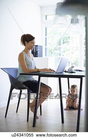 Mid adult mother typing on laptop with toddler daughter under the table View Large Photo Image Stock Photography - Mid adult mother typing on laptop with toddler daughter under the table. Fotosearch