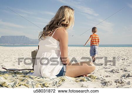 Mid adult mother watching young son play on beach, Cape Town, Western Cape, South Africa View Large Photo Image Stock Image - Mid adult mother watching young son play on beach, Cape Town, Western Cape, South Africa. Fotosearch