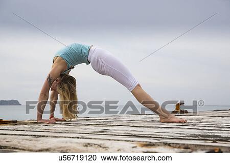Mid adult woman bending over backwards practicing yoga on wooden sea pier View Large Photo Image Stock Image - Mid adult woman bending over backwards practicing yoga on wooden sea pier. Fotosearch